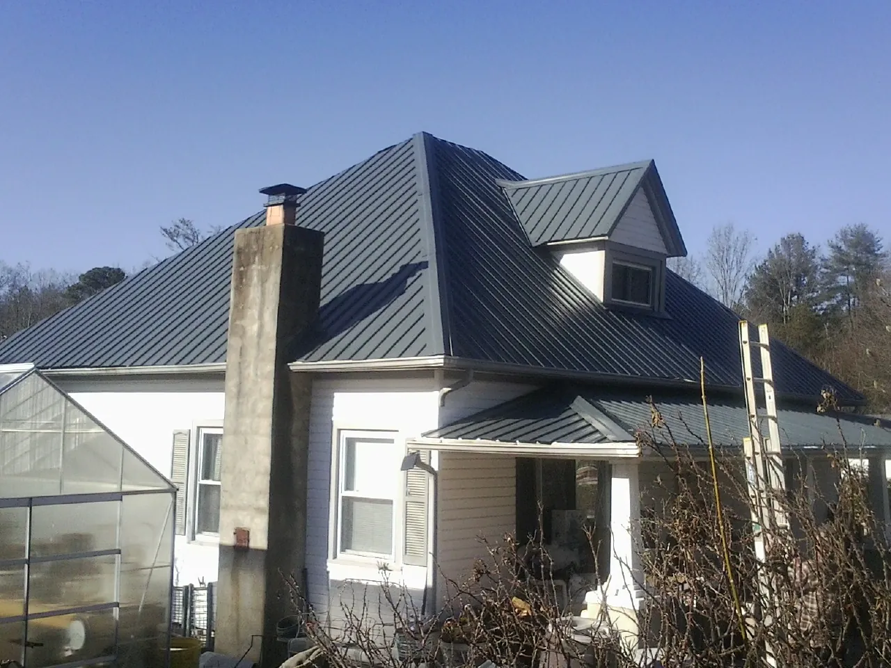 Dark blue standing seam metal roof on a white farmhouse with dormer — Slate & Tile Roof Repair by Roofing Brothers in Crawfordsville