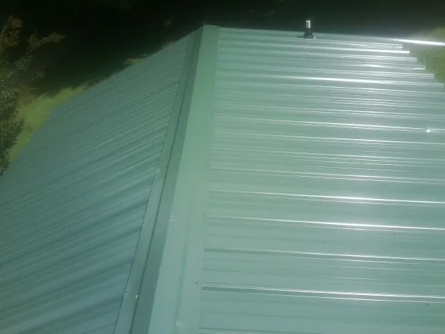 New green metal panels meeting at the ridge of a roof — Flat Roof Repair work by our crew in Crawfordsville