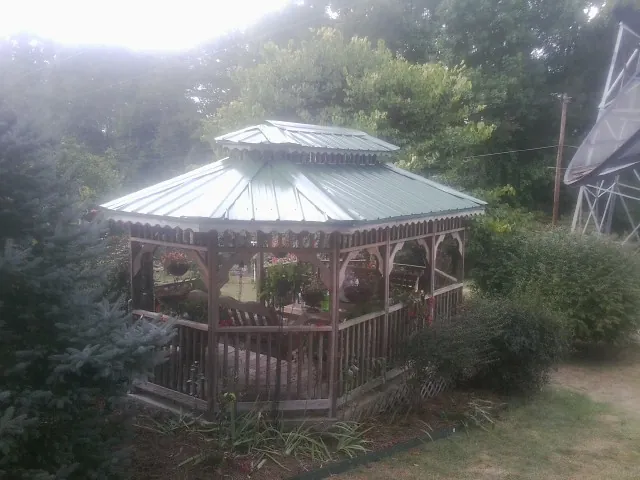 Green metal roof on a backyard gazebo surrounded by garden beds in Crawfordsville