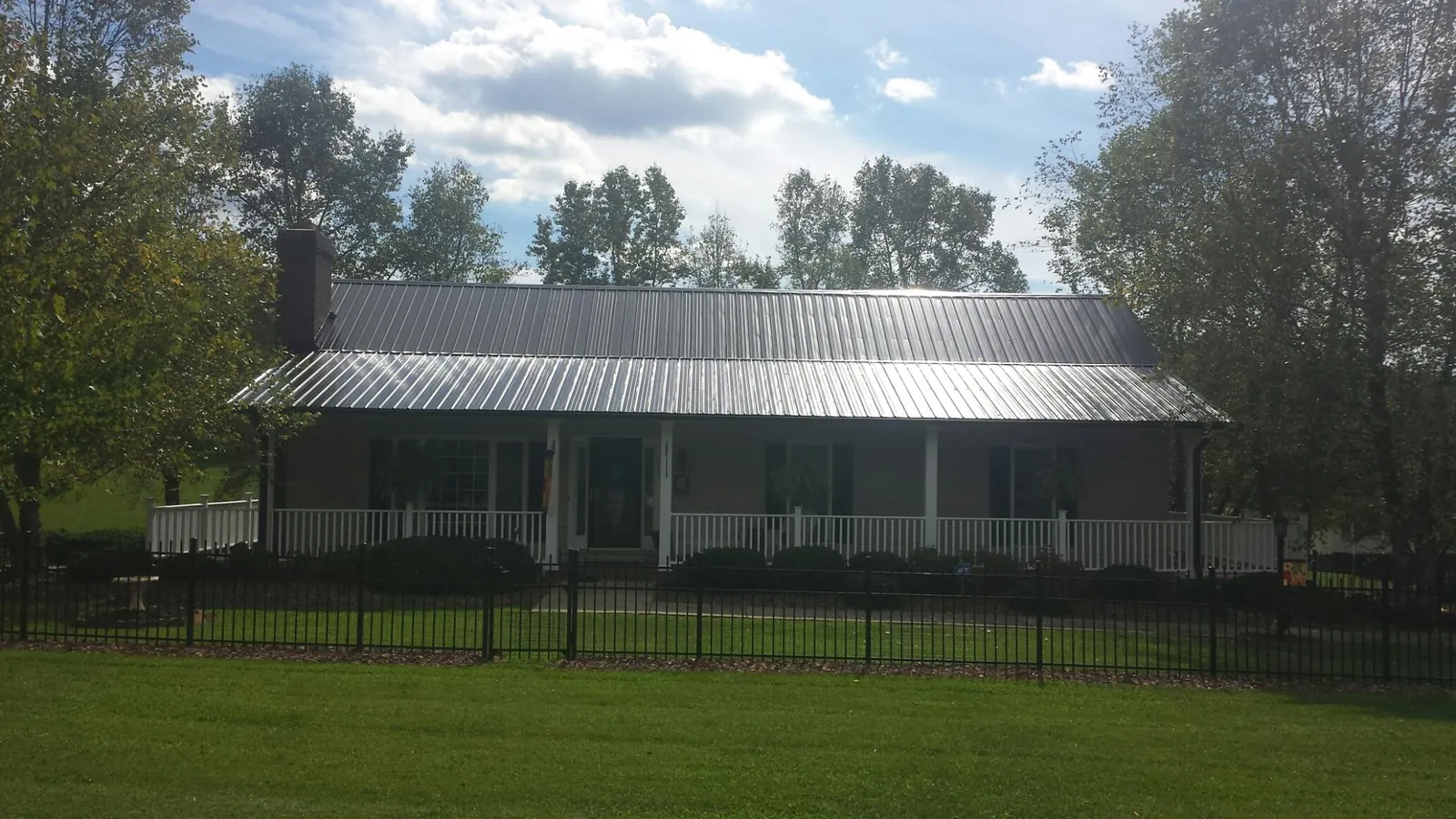 Gray metal roof on a brick ranch with a full width front porch — Gutter Guard Installation work by our crew in Crawfordsville