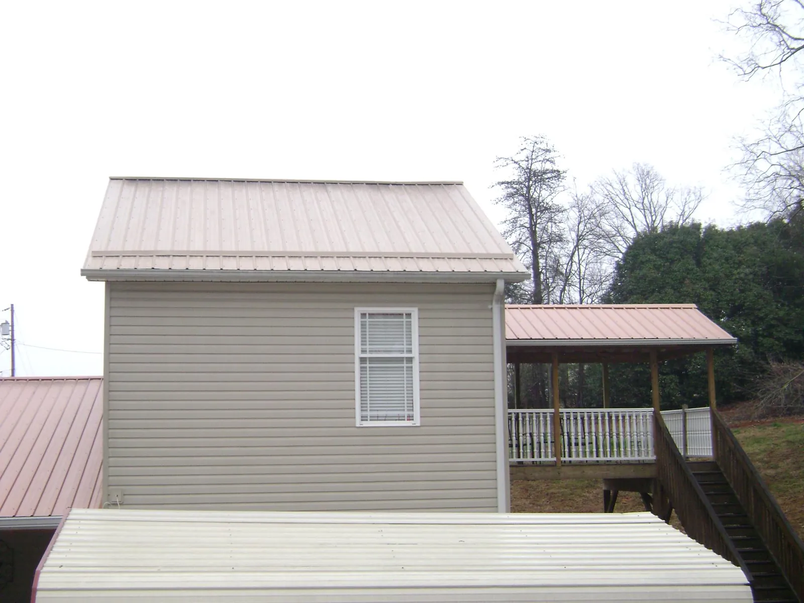 Tan metal roofs on a two story addition and attached porch, from a Roof Replacement job in Crawfordsville